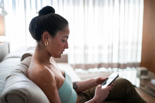 Young woman using mobile phone sitting on the couch at home