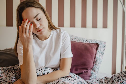 A sad young woman in bed suffers from depression