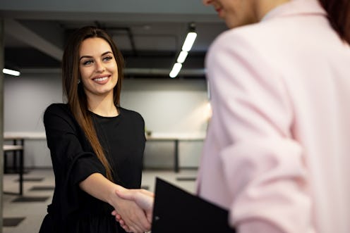 Smiling young Caucasian businesswoman shake hand of colleague close deal after succesful meeting in ...