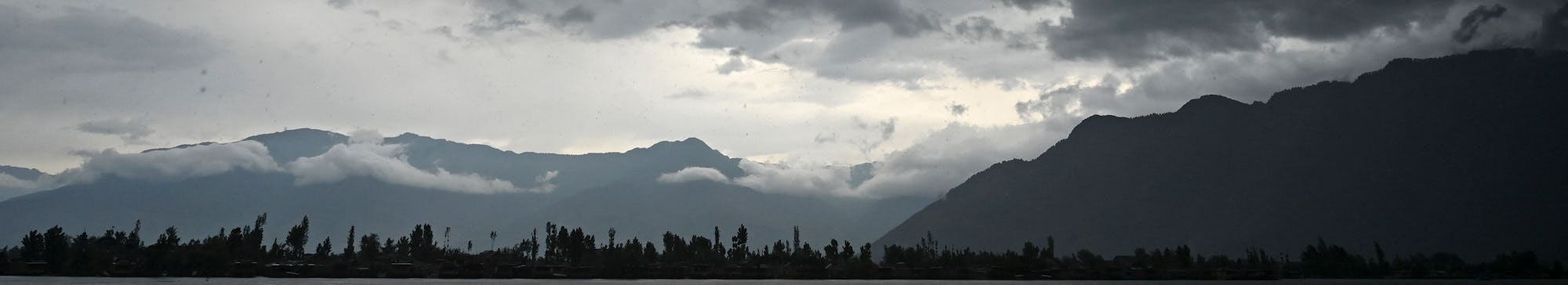 A man steers a boat as dark clouds loom over Dal Lake during a rainfall in Srinagar on June 1, 2021....