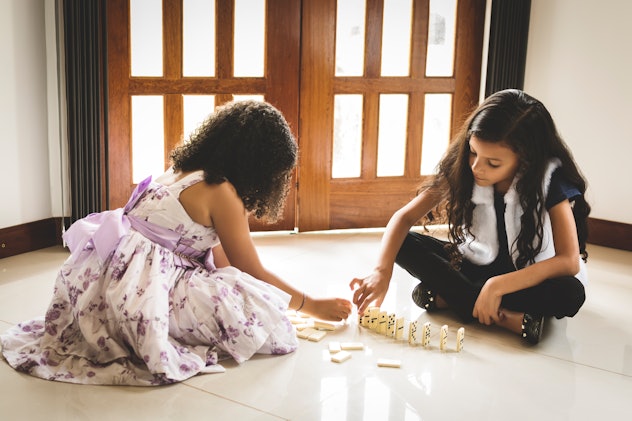 Two cute girls, about six years old, sitting on the floor and playing domino