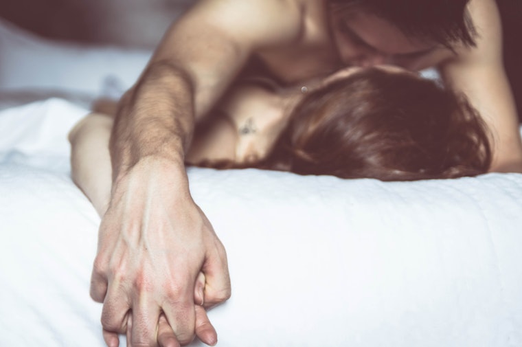 Couple holds hands in bed during sex, a strong indicator of positive body language during sex.