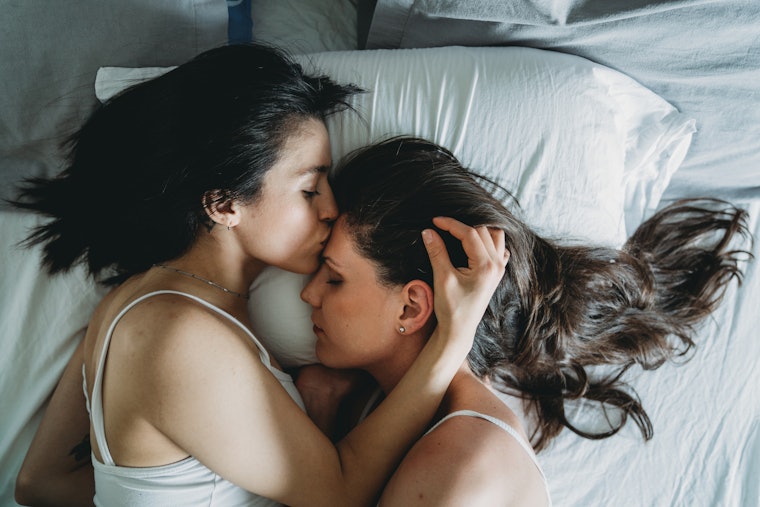 High angle view of two young adult women kissing together. One girl is kissing on the forehead the other girl. Hispanic and South American ethnicities. "Stay at home" concept.