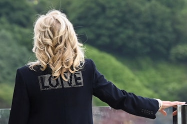 US First Lady Jill Biden, wearing a jacket with the words 'Love' on the back, looks out over the sea...
