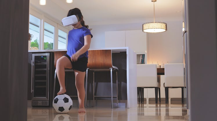 Little girl playing soccer using a Virtual Reality set