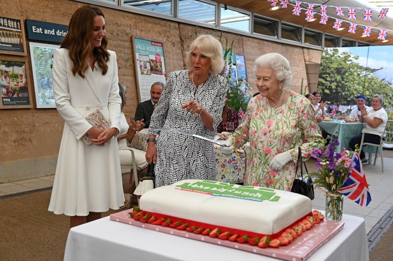 ST AUSTELL, ENGLAND - JUNE 11: Queen Elizabeth II (C) considers cutting a cake with a sword, lent to...