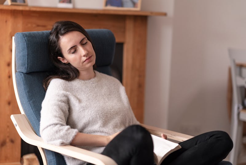 Young woman relaxing on the seat, she is falling asleep while reading a book