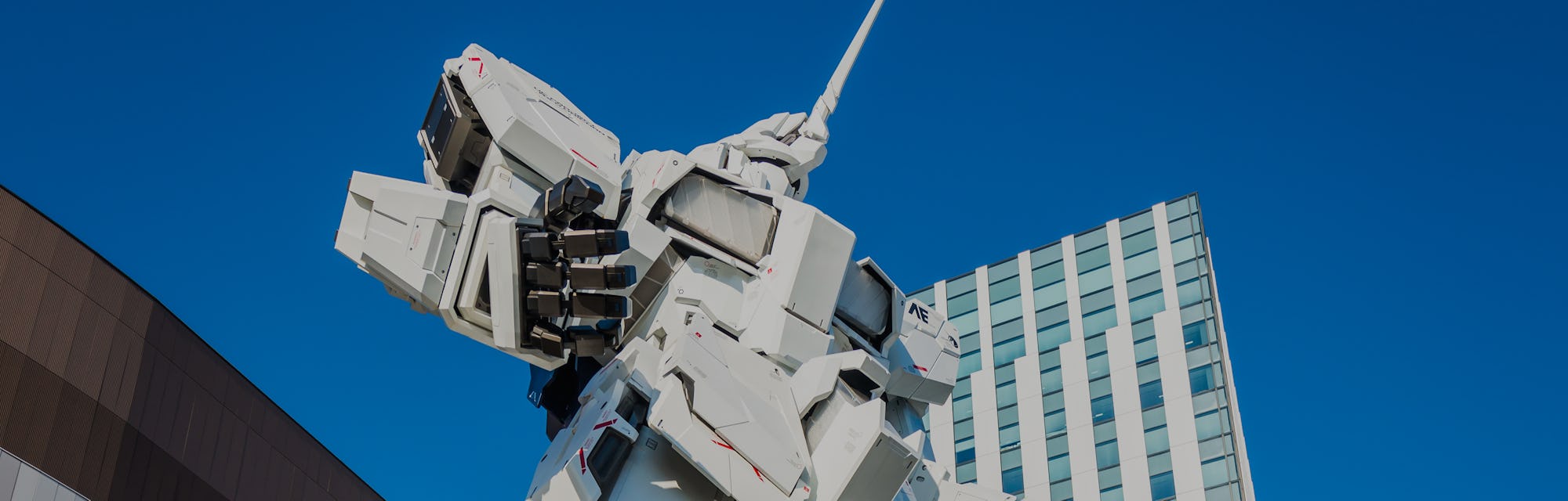 Tourists and shoppers dwarfed by the giant Unicorn Gundam statue outside DiverCity Tokyo Plaza mall ...