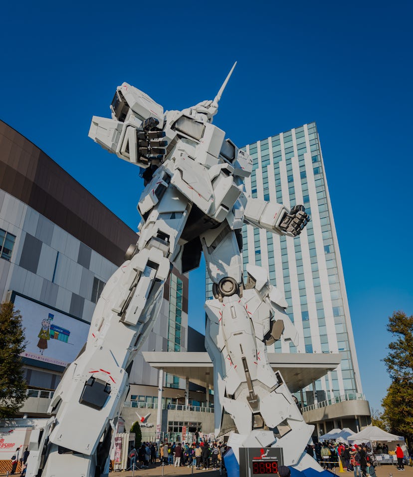 Tourists and shoppers dwarfed by the giant Unicorn Gundam statue outside DiverCity Tokyo Plaza mall ...