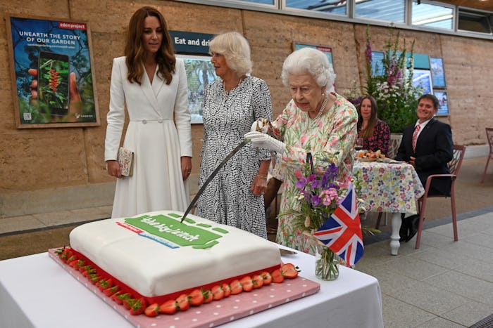 Queen Elizabeth cuts a cake with a sword lent to her by The Lord-Lieutenant of Cornwall on June 11 i...