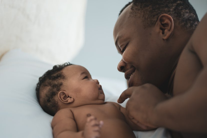 Happy affectionate african american father embracing his newborn baby daughter(2-5 months) lying on ...
