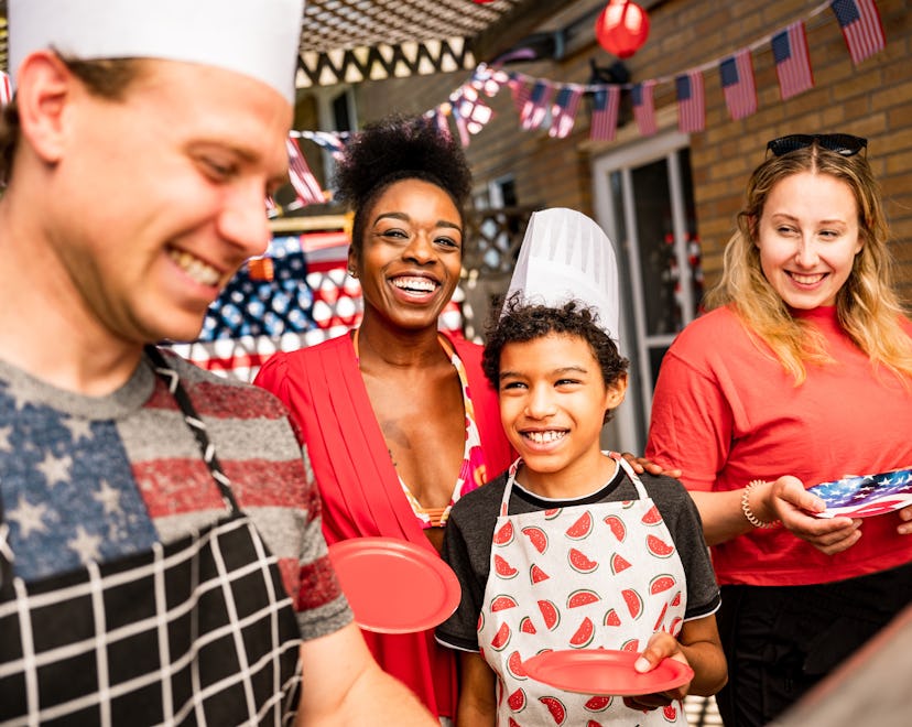 People waiting for burgers at the BBQ grill for outdoor 4th July backyard celebration. Multi racial,...