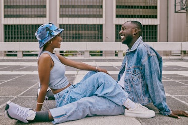 A trendy young Black couple sitting on the ground wearing trendy, baggy denim jeans and a denim jack...