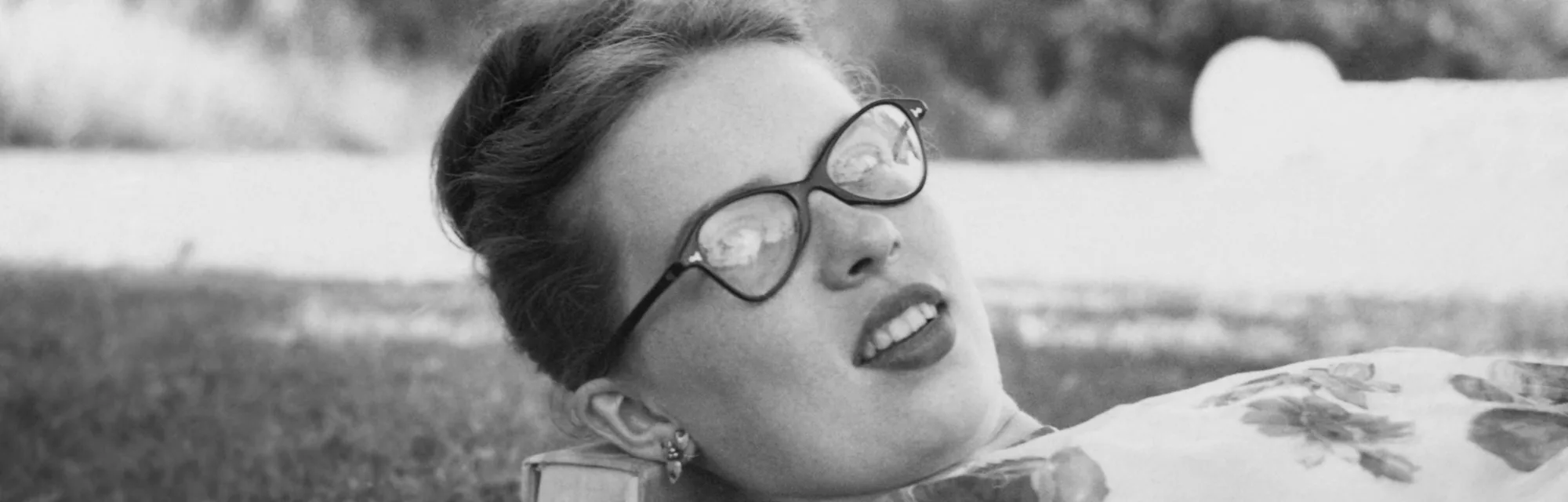 Retro teenager lying down on books in the park