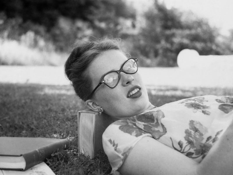 Retro teenager lying down on books in the park
