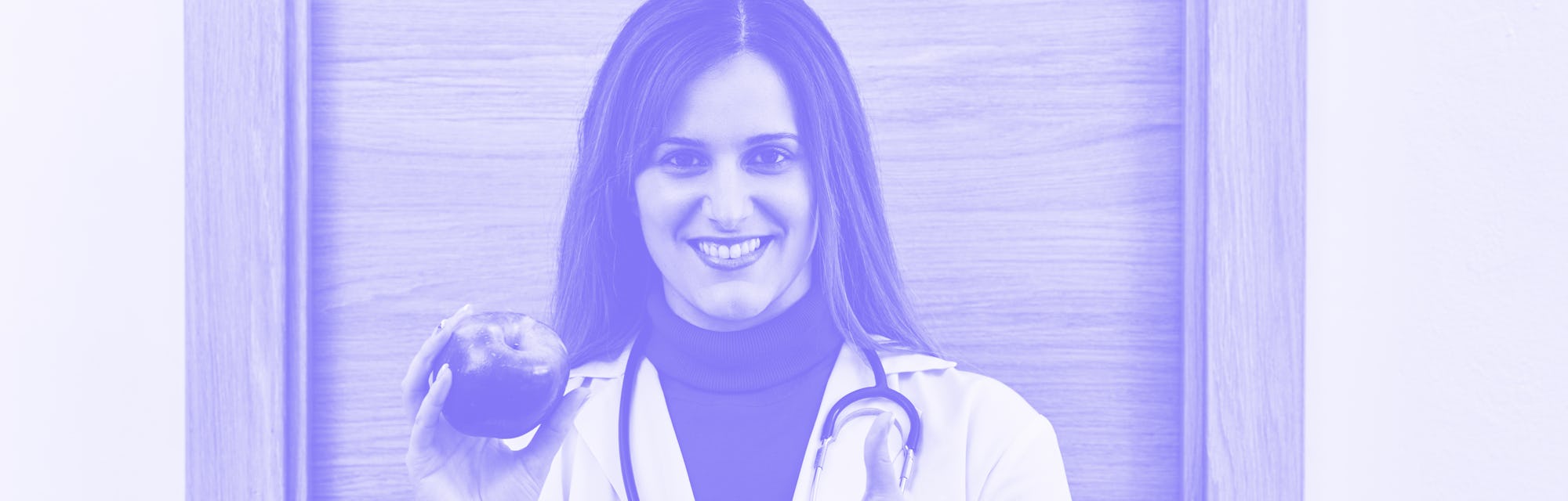 Portrait of young female doctor holding an apple in her hand. Concept of healthy food and nutrition.