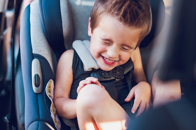 little boy laughing in his car seat