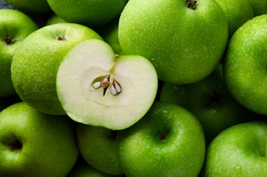 close-up green apples background, half apple on whole green apples