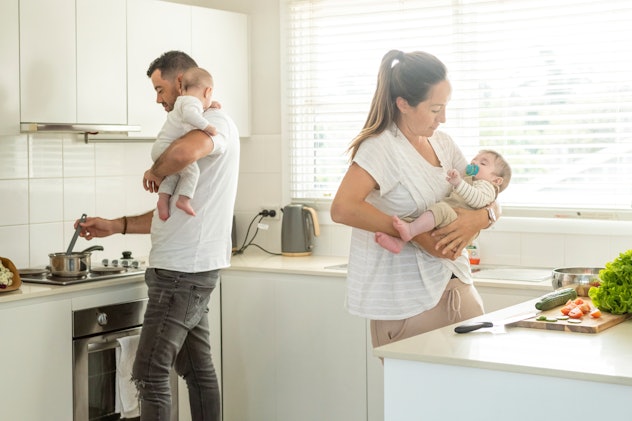 An attractive couple cook dinner together in a modern looking kitchen. They are each holding one of ...