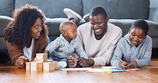 mom, dad, and two kids hanging out drawing and playing on the floor