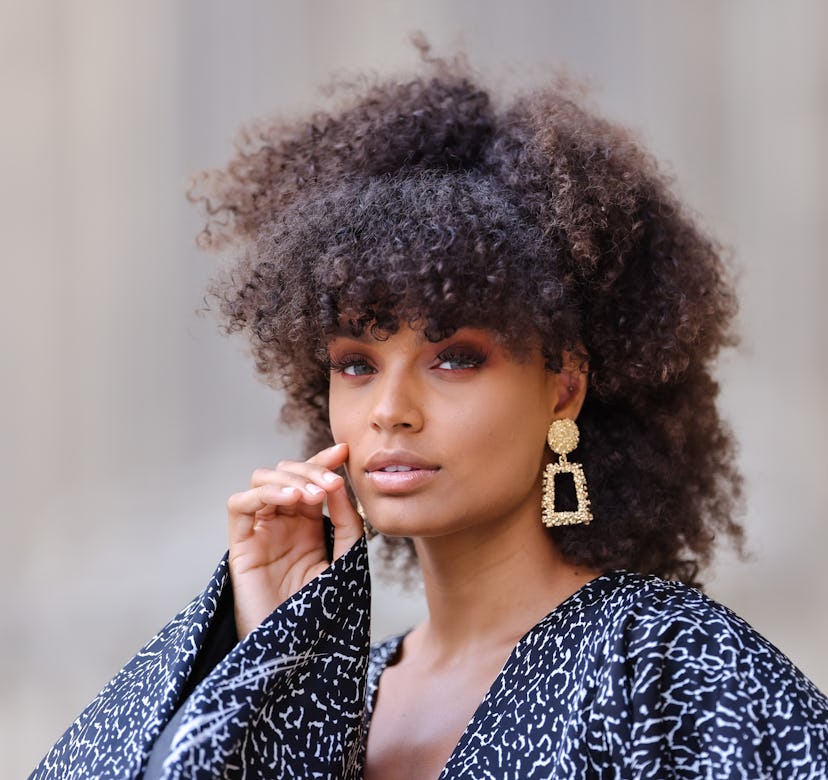PARIS, FRANCE - JUNE 08: Alicia Aylies wears gold and rhinestones earrings, a black and white print ...