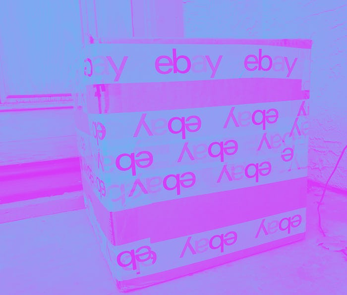 Photograph of a large cardboard shipping box secured with packing tape featuring the eBay logo on a ...
