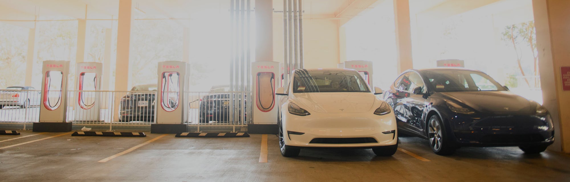 Tesla Inc. electric vehicles charge at the company's supercharger station inside a parking garage on...