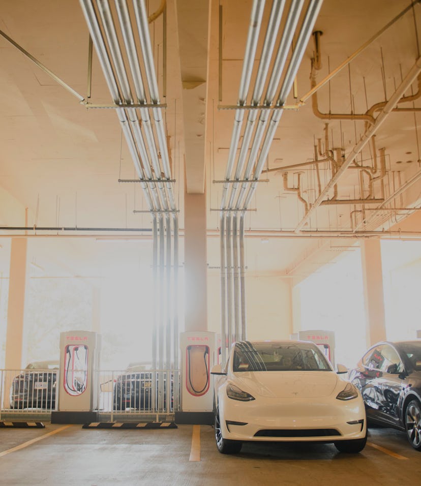 Tesla Inc. electric vehicles charge at the company's supercharger station inside a parking garage on...