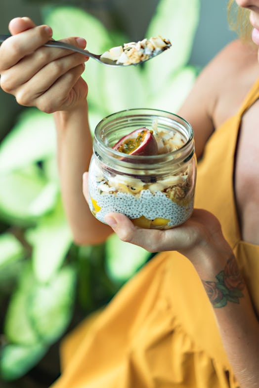 Young woman holding a chia pudding.  Want to learn how to poop more or how to poop everyday? Eating ...