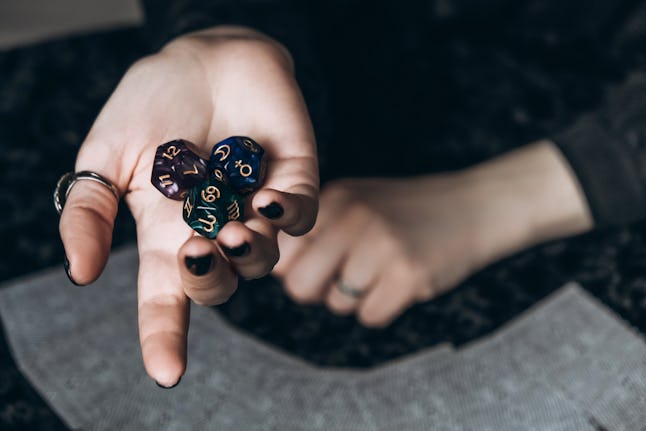 Beautiful astrological cube with different signs and numbers in woman hand on a dark background with tarot cards