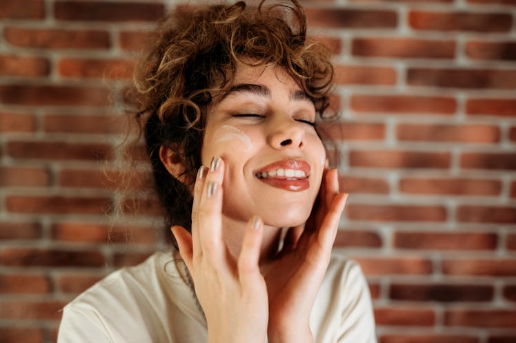 Close up of a beautiful young girl while putting on makeup and grooming her face
