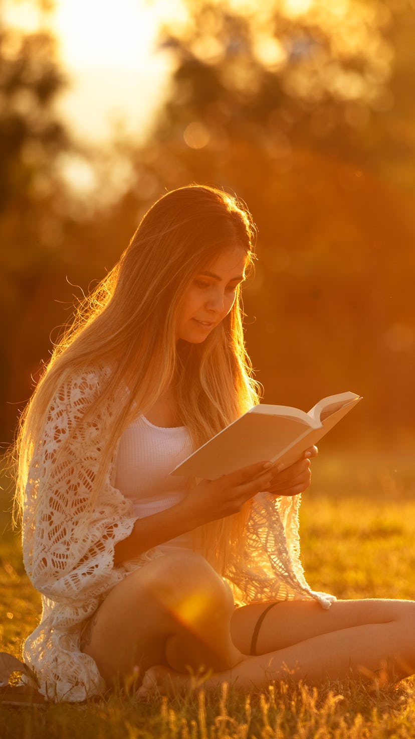 young woman studying on the grass at sunset