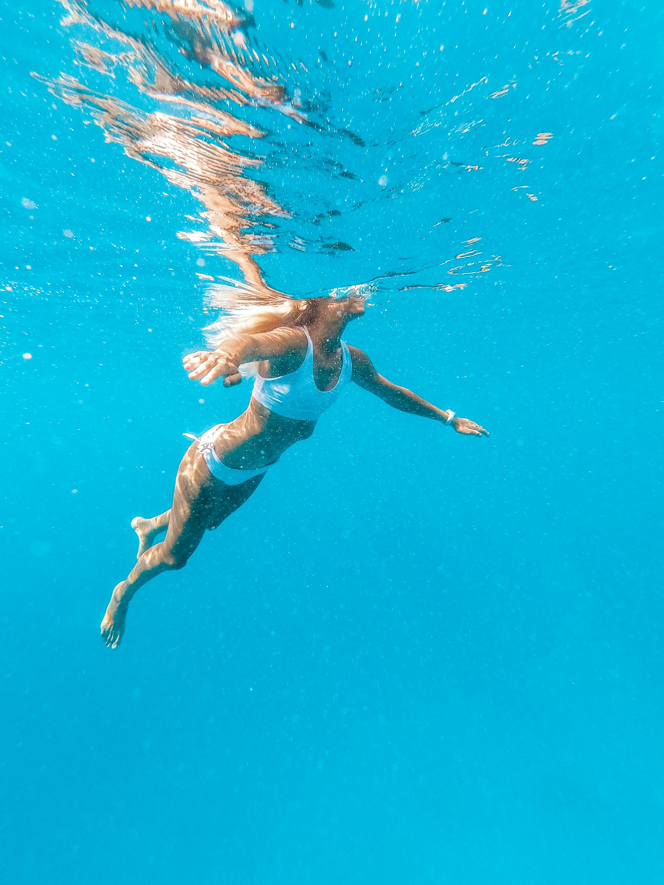 A woman swims underwater. Swimming workout benefits.