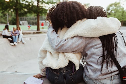 Two friends lean on each other for support. This article details how to help someone who is insecure...