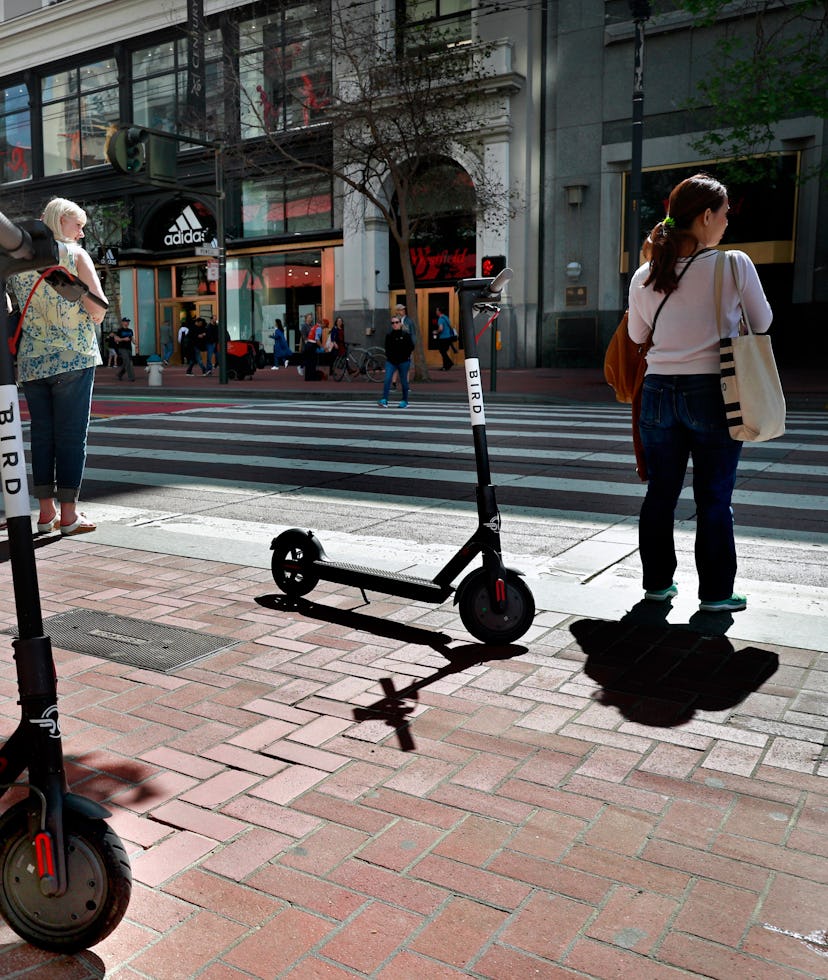 Two Bird scooters parked along Market St. as pedestrians wait at  the crosswalk as seen on Mon. Apri...