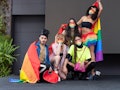 Group of friends of different sexual orientations celebrate gay pride wearing their rainbow flag and...