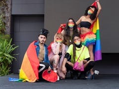 Group of friends of different sexual orientations celebrate gay pride wearing their rainbow flag and...