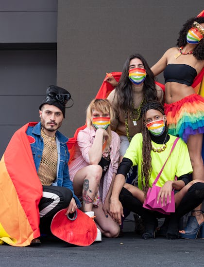 Group of friends of different sexual orientations celebrate gay pride wearing their rainbow flag and...