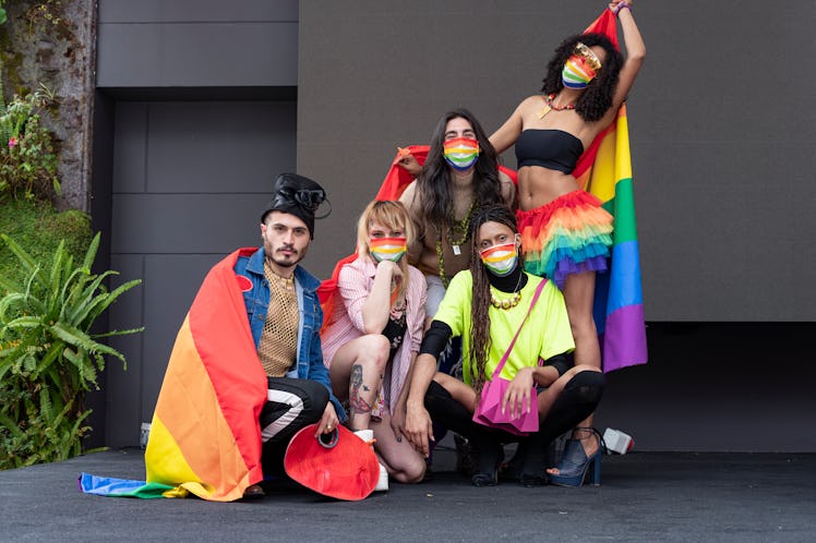 Group of friends of different sexual orientations celebrate gay pride wearing their rainbow flag and...