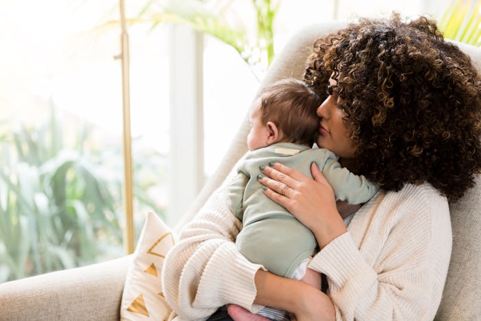 Loving mom rocks her sleepy baby in a comfortable rocking chair.