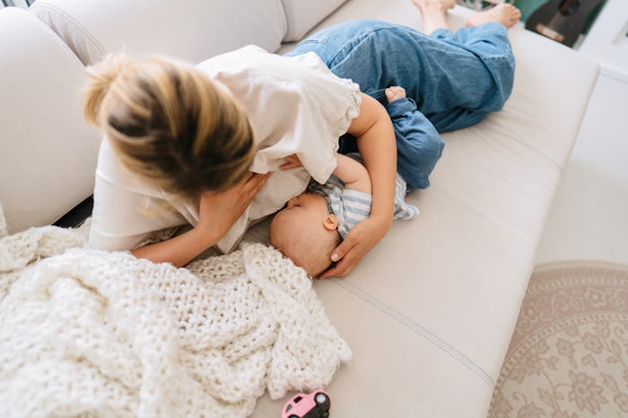 Photo of young woman breastfeeding her baby at home
