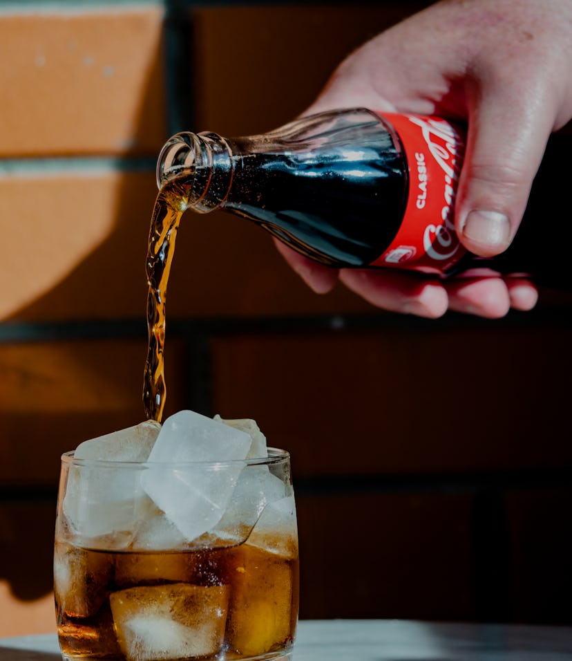 UKRAINE - 2021/04/29: In this photo illustration a Coca-Cola soft drink being poured into a glass wi...
