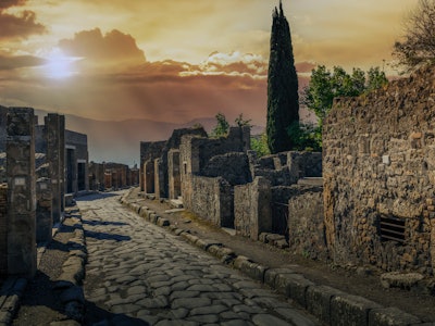Old stones paved road at sunset in Pompeii Archaeological site.