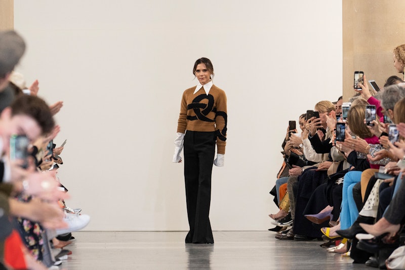 Victoria Beckham on stage following the runway presentation of a new fashion collection. She is stan...