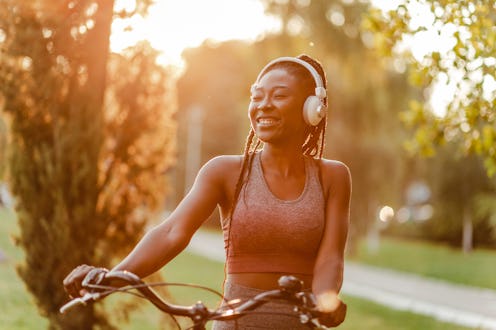 Portrait of a modern smiling African American woman in the park with her bicycle