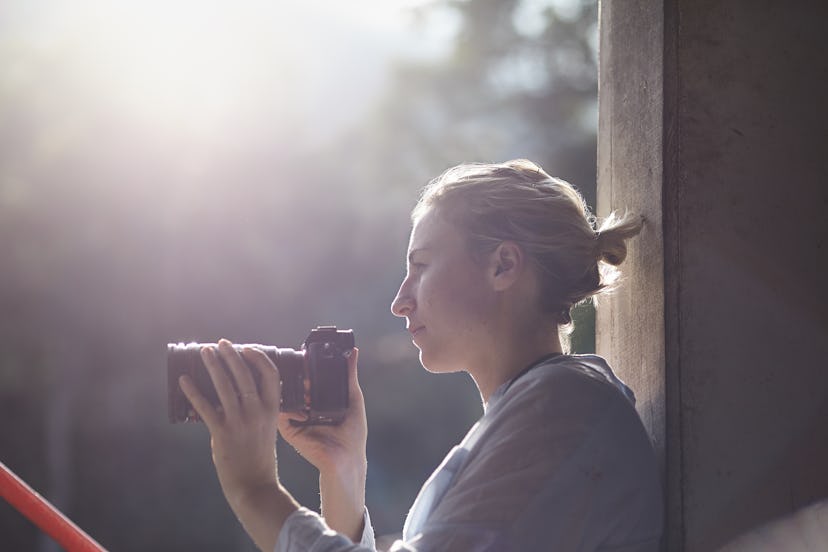 female photographer relaxing in hazy backlight, thinking and relaxing, looks happy and thoughtful