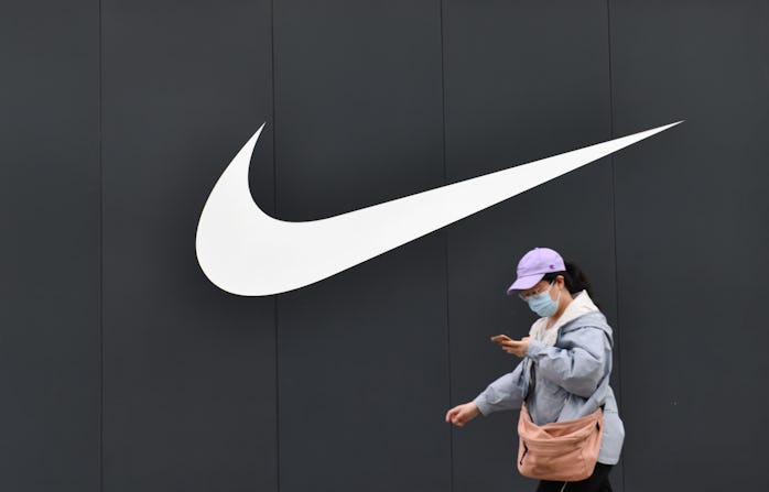 BEIJING, CHINA - MAY 10, 2021 - A pedestrian passes in front of the Nike logo of the Nike flagship s...