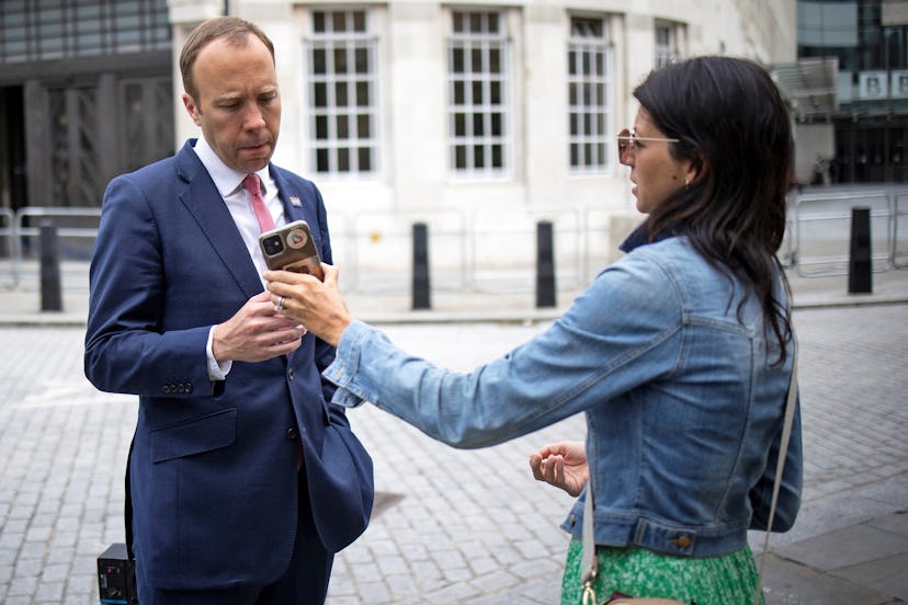 Britain's Health Secretary Matt Hancock (L), looks at the phone of his aide Gina Coladangelo as they...