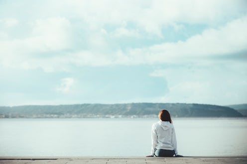 Back view of one teenager girl thinking alone and watching the sea sitting at sea side with the hori...