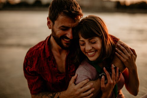 Young couple looking at each other on the beach at late sunset. Love is in the air. Urban people hav...